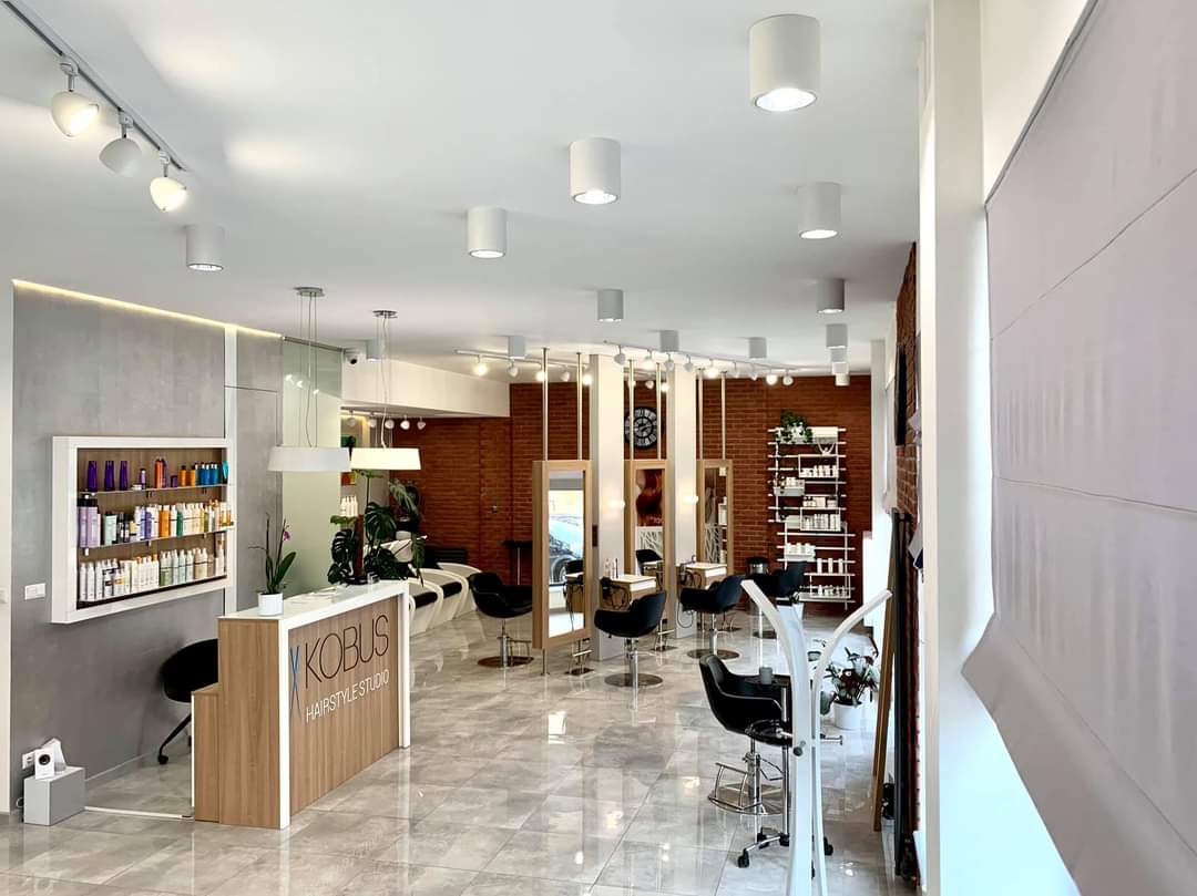 Wnętrze Kobus Hairstyle Studio - recepcja z logo, jasne wnętrze z lustrami i ceglaną ścianą